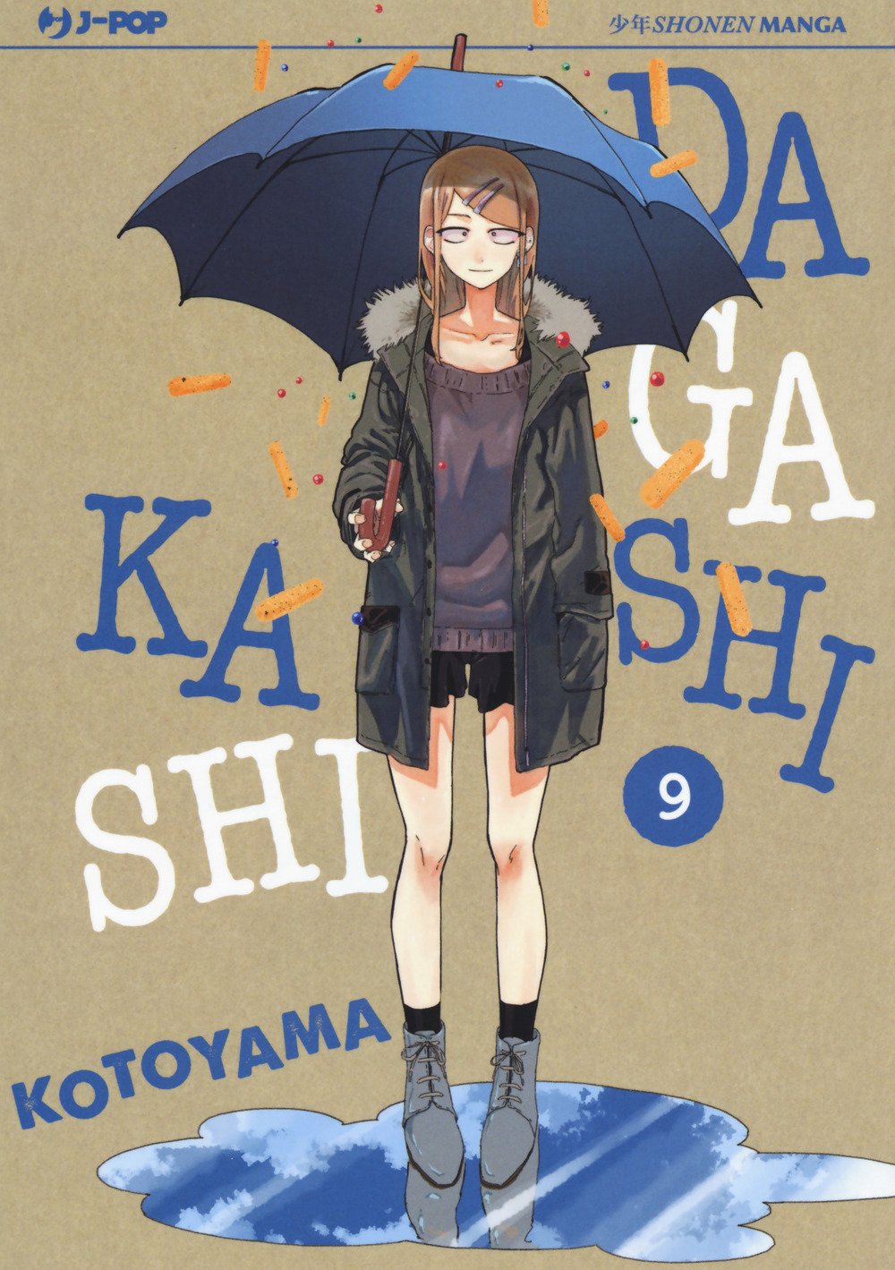 Copertina del nono volume del manga 'Dagashi Kashi' di Kotoyama, edito da J-POP Manga. L'illustrazione ritrae a figura intera Saya Endou con giaccone invernale che tiene un ombrello blu sotto una pioggia di snack salati, affiancata dal titolo in lettere blu e bianche e dal numero 9 racchiuso in un cerchio blu.