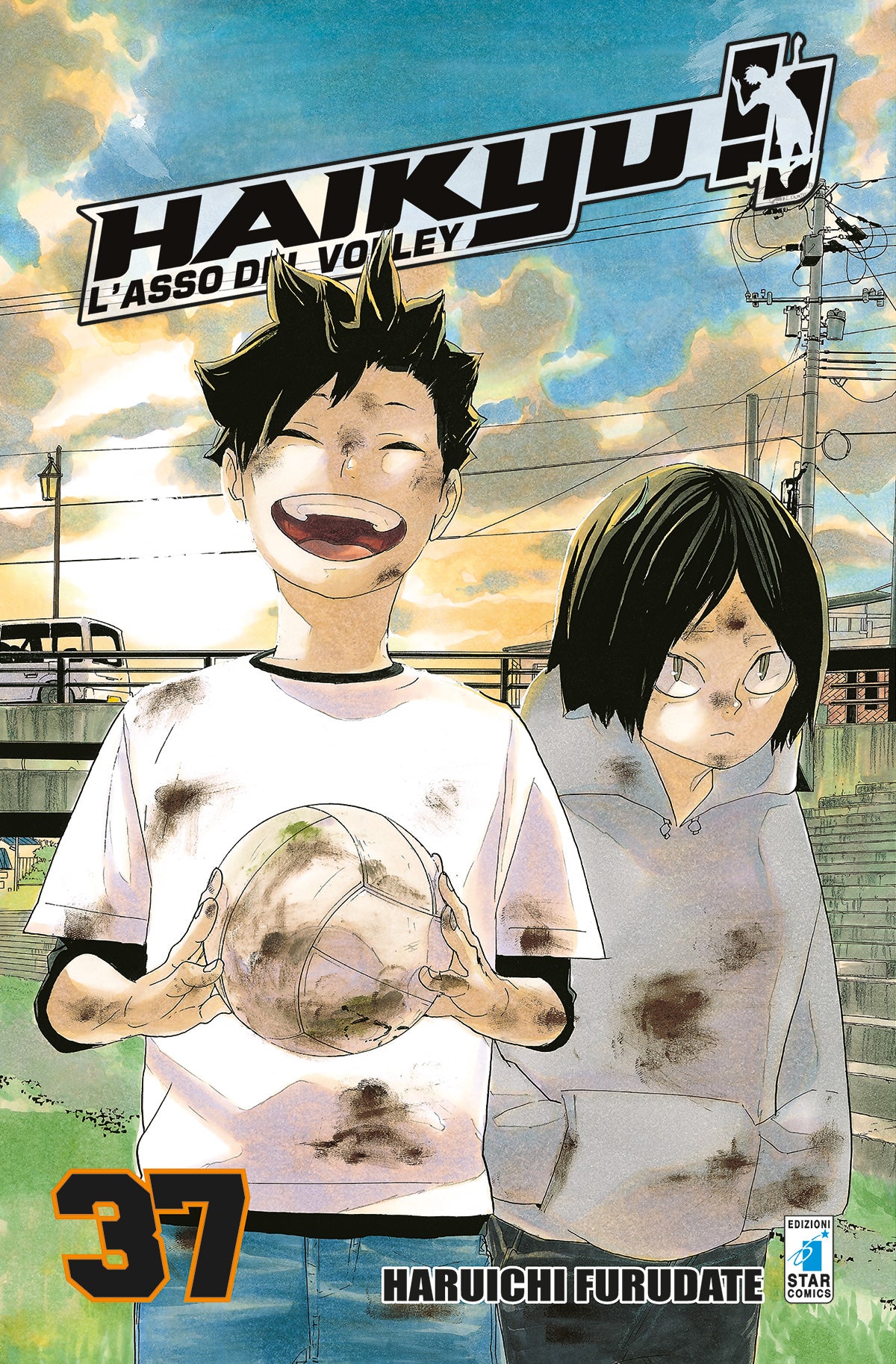Copertina del manga Haikyu!! Vol. 37 edito da Star Comics. In un'immagine carica di nostalgia e calore, sono ritratti i giovani Tetsuro Kuroo e Kenma Kozume da bambini. Entrambi sono sporchi di fango; Kuroo sorride ampiamente reggendo un pallone da pallavolo, mentre il piccolo Kenma lo osserva con la sua classica espressione mite. Lo sfondo mostra un tramonto dorato su un paesaggio urbano. In basso a sinistra spicca il numero 37.