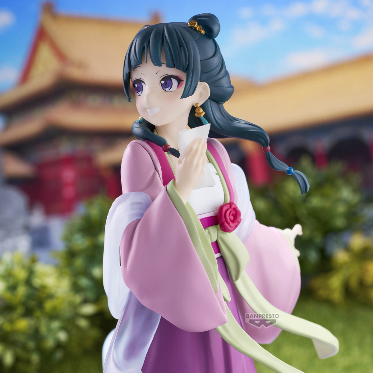 Figure di Maomao della serie The Apothecary Diaries prodotta da Banpresto. La ragazza indossa un elegante abito tradizionale rosa e viola, si volta sorridendo e tiene in mano un piccolo foglio.