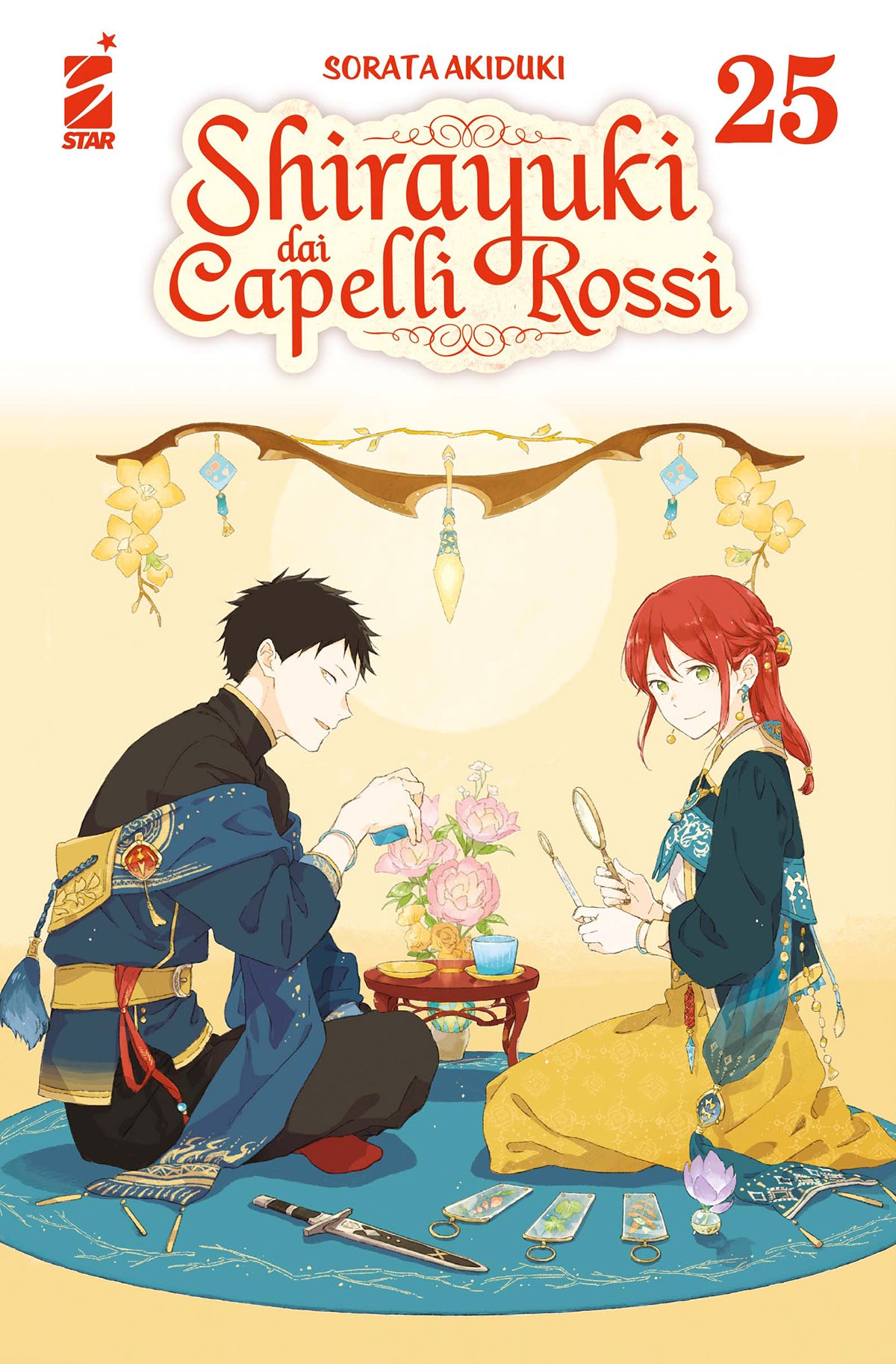 Copertina del venticinquesimo volume in italiano del manga shojo fantasy 'Shirayuki dai Capelli Rossi' di Sorata Akiduki, edito da Star Comics. L'illustrazione ritrae in primo piano Obi a sinistra con abiti eleganti blu e gialli e Shirayuki a destra dai capelli rossi legati con abito coordinato oro e ottanio, seduti l'uno di fronte all'altra su un tappeto blu con fiori rosa al centro, piccoli strumenti e un pugnale a terra, sormontati dal titolo SHIRAYUKI DAI CAPELLI ROSSI in rosso, dal numero 25 in alto a