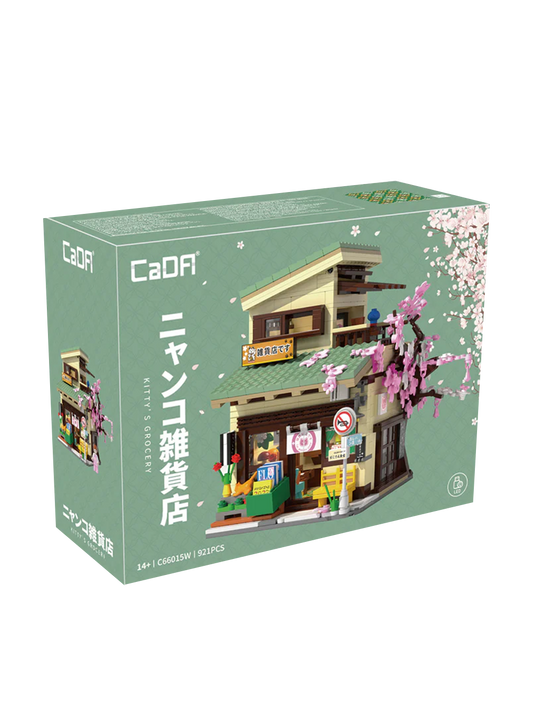 Scatola e modello assemblato del set di costruzioni CaDA "Kitty's Grocery" (C66015W). Raffigura un tipico negozietto giapponese a due piani con tetto verde, un grande albero di ciliegio rosa fiorito sul lato, espositori esterni con riviste, un gatto arancione e l'interno del negozio visibile grazie a una parete apribile. Sulla scatola è indicata la presenza di 921 pezzi e del sistema LED.