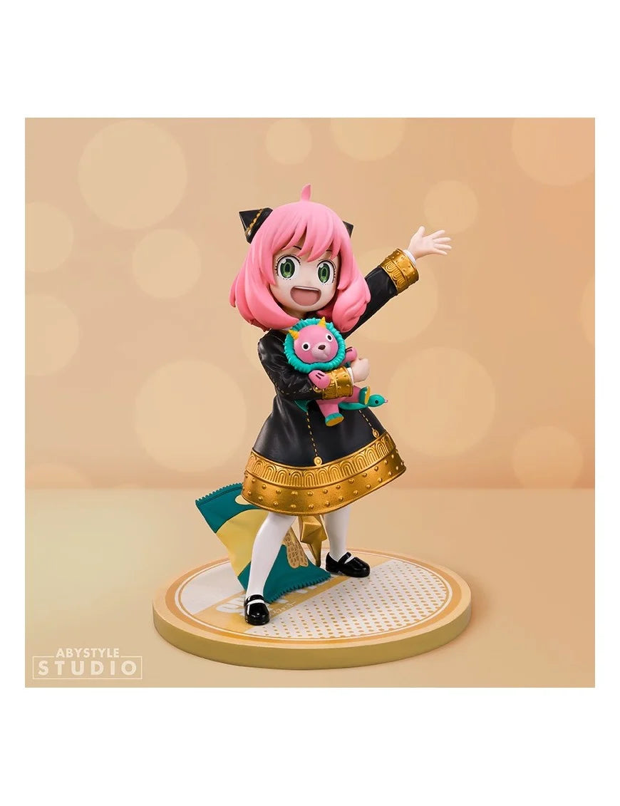Figure della linea Super Figure Collection di Anya Forger da Spy x Family prodotta da Abystyle Studio; il personaggio indossa l'uniforme scolastica nera e oro, tiene in braccio il peluche rosa Chimera e ai suoi piedi, sulla base, c'è un sacchetto di noccioline.