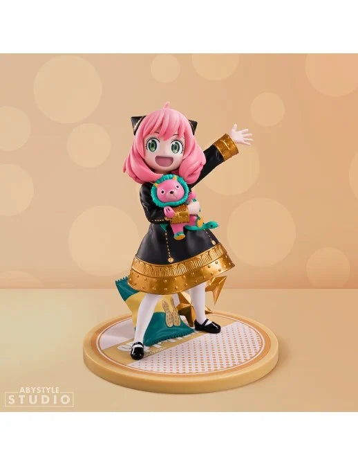 Figure della linea Super Figure Collection di Anya Forger da Spy x Family prodotta da Abystyle Studio; il personaggio indossa l'uniforme scolastica nera e oro, tiene in braccio il peluche rosa Chimera e ai suoi piedi, sulla base, c'è un sacchetto di noccioline.