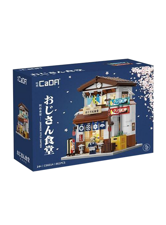 Scatola blu del set di costruzioni CaDA "Japanese Style Canteen", decorata con delicati petali di ciliegio. Al centro spicca il modello assemblato: un tipico ristorante giapponese a due piani con tetto marrone, tende blu all'ingresso, due bandiere a forma di carpa e la minifigure di un anziano cuoco davanti alla porta. In basso sono indicati i pezzi (861PCS) e l'icona del sistema LED incluso.