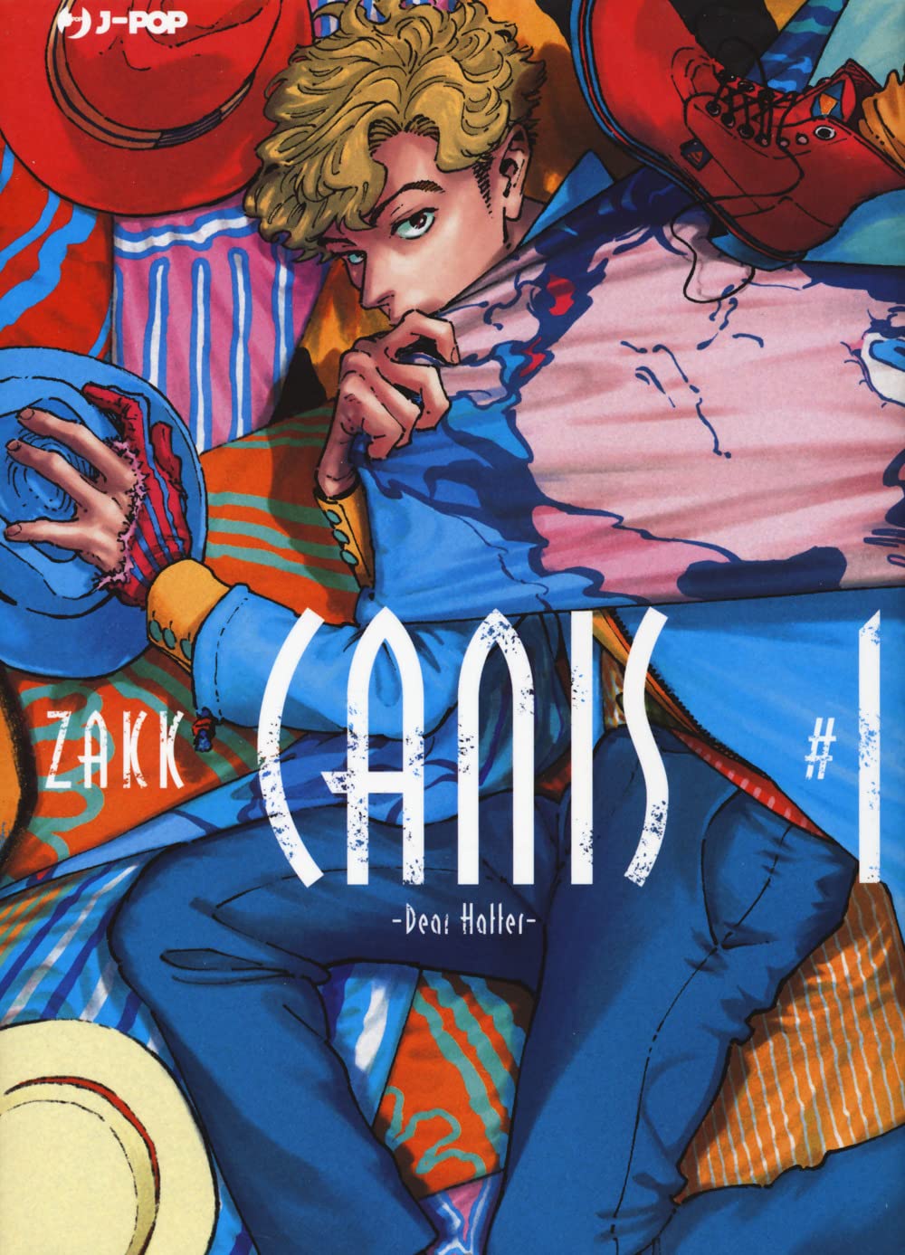 Copertina del primo volume del manga Boys' Love 'Canis - Dear Hatter -' di ZAKK, edito da J-POP Manga. L'illustrazione ritrae un ragazzo dai capelli mossi biondi sdraiato tra teli e stoffe variopinte e cappelli, vestito con una giacca azzurra e pantaloni blu, sormontato dal titolo 'CANIS #1 -Dear Hatter-' stilizzato in bianco.