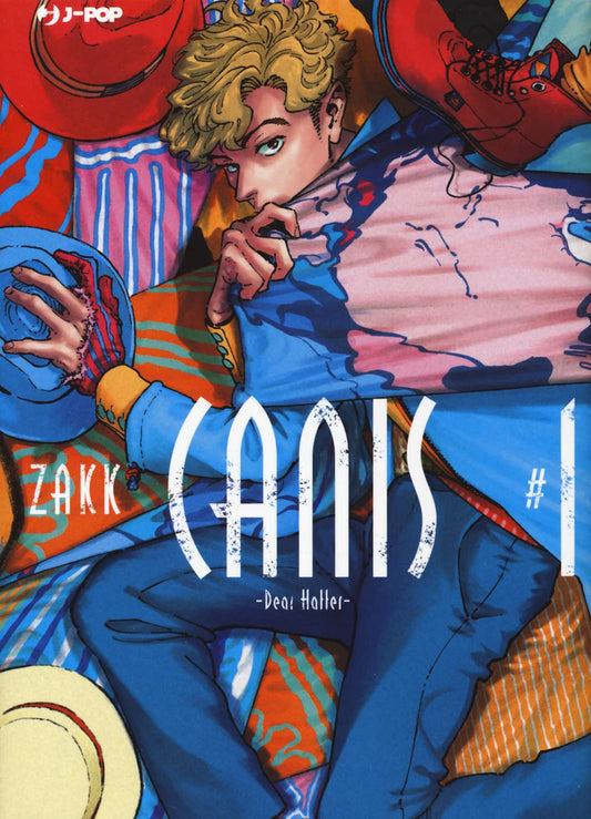 Copertina del primo volume del manga Boys' Love 'Canis - Dear Hatter -' di ZAKK, edito da J-POP Manga. L'illustrazione ritrae un ragazzo dai capelli mossi biondi sdraiato tra teli e stoffe variopinte e cappelli, vestito con una giacca azzurra e pantaloni blu, sormontato dal titolo 'CANIS #1 -Dear Hatter-' stilizzato in bianco.