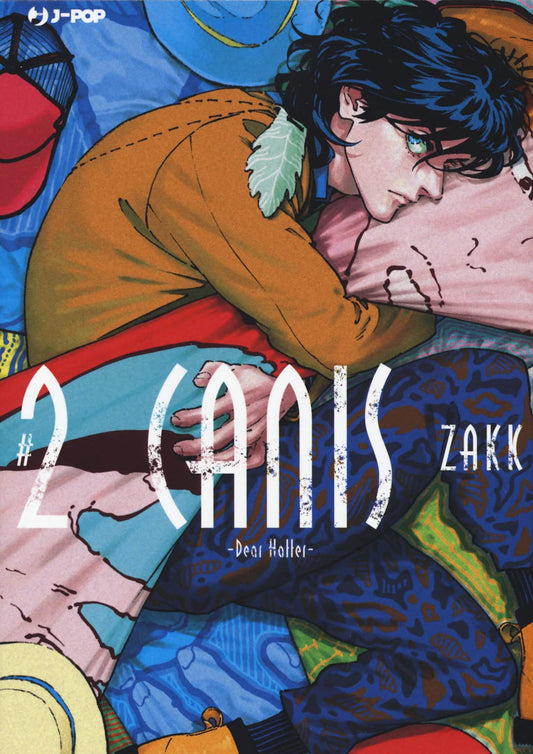 Copertina del secondo volume del manga Boys' Love 'Canis - Dear Hatter -' di ZAKK, edito da J-POP Manga. L'illustrazione ritrae un ragazzo dai capelli scuri e mossi rannicchiato su un cuscino rosa tra variopinti cappelli e stoffe, vestito con una giacca color senape e pantaloni blu a fantasia, sormontato dalla scritta '#2 CANIS -Dear Hatter-' stilizzata in bianco.