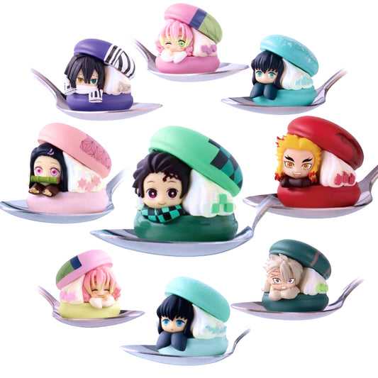 Assortimento di mini figure Gashapon di Demon Slayer della linea Macaron Chara, con i personaggi ritratti all'interno di colorati macaron appoggiati su dei cucchiaini d'argento.