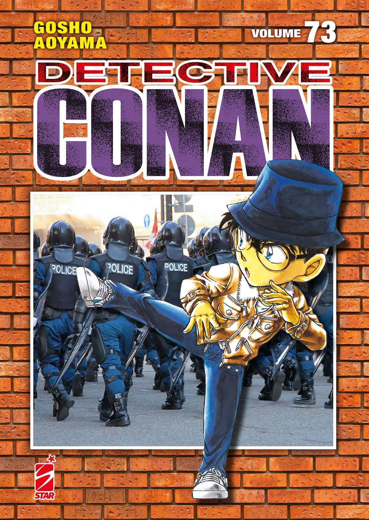 Copertina del settantatreesimo volume del manga 'Detective Conan New Edition' di Gosho Aoyama, edito da Star Comics con sfondo a trama di mattoni rossi. L'illustrazione principale ritrae al centro Conan Edogawa vestito con giacca di pelle dorata e cappello blu mentre sferra un calcio volante, sovrapposto a un riquadro fotografico con agenti di polizia antisommossa, affiancato dal titolo 'DETECTIVE CONAN', dall'indicazione 'VOLUME 73' e dal logo Star Comics in basso a sinistra.   