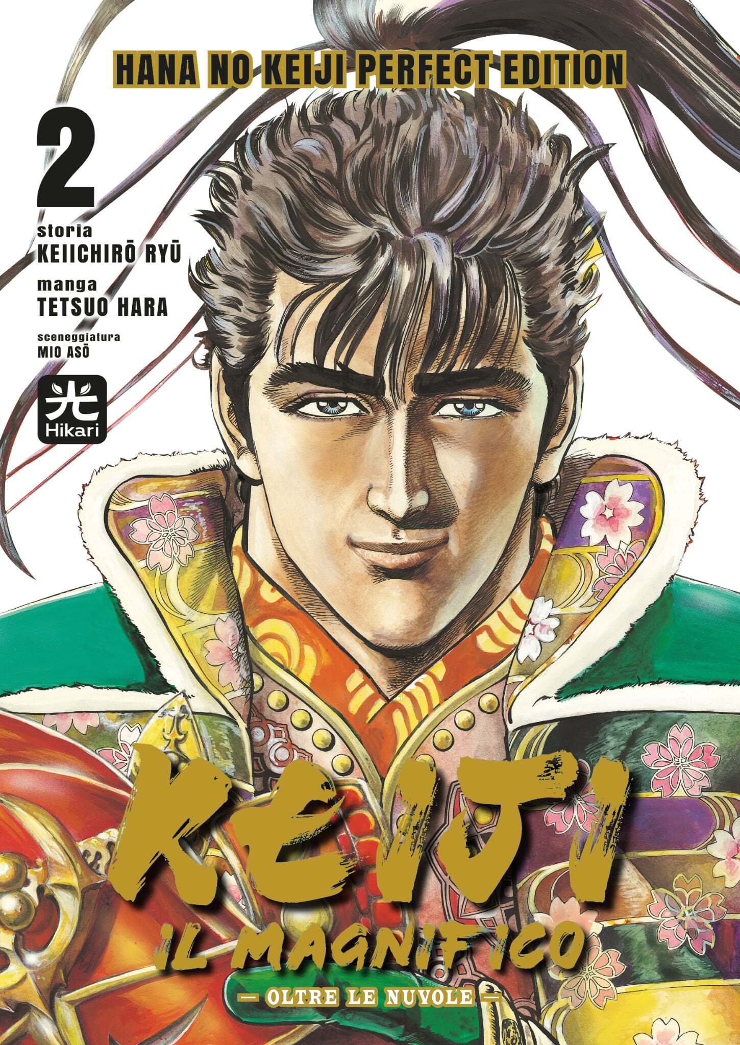 Copertina del secondo volume del manga Keiji il Magnifico in edizione Variant Perfect Edition. In primo piano è raffigurato il carismatico samurai Maeda Keiji con un sorriso accennato, lo sguardo fiero e i capelli castani raccolti in un'alta coda. Indossa una veste sfarzosa e colorata con decorazioni dorate, verdi e motivi di fiori di ciliegio. In basso campeggia il titolo Keiji il Magnifico scritto con grandi caratteri dorati.