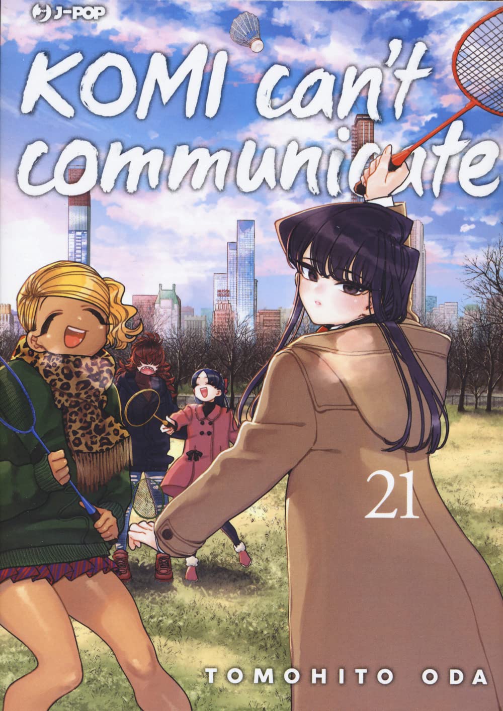 Copertina del ventunesimo volume del manga 'Komi Can't Communicate' edito da J-POP Manga, con Komi e Manbagi che giocano a badminton in un parco con lo sfondo dei grattacieli di New York.