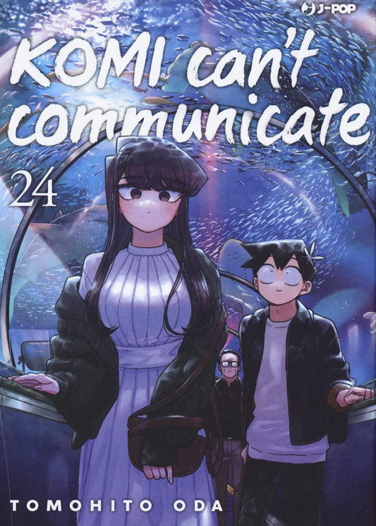 Copertina del ventiquattresimo volume del manga 'Komi Can't Communicate' di Tomohito Oda, edito da J-POP Manga. L'illustrazione ritrae Shouko Komi in abito bianco lungo e cardigan scuro affiancata da Hitohito Tadano all'interno del tunnel panoramico di un acquario circondati da pesci azzurri, sormontati dal titolo in bianco e dal numero 24 in alto a sinistra.