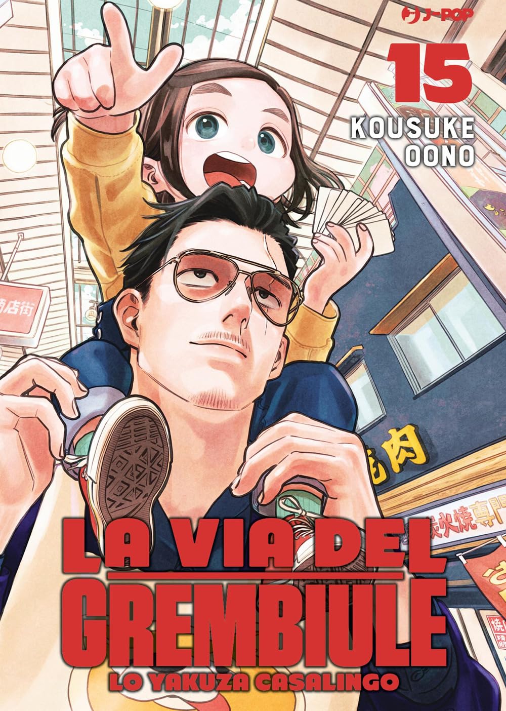 Copertina del manga La Via Del Grembiule volume 15 edito da J-POP; l'illustrazione mostra Tatsu con gli occhiali da sole che porta una bambina sorridente sulle spalle, tenendo in mano delle carte.