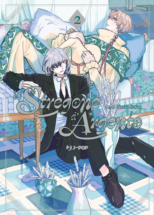Copertina del manga Lo Stregone D'Argento volume 2. L'illustrazione mostra due figure maschili eleganti in una stanza: in primo piano un giovane seduto a terra con capelli corti grigio argento e un completo scuro, mentre alle sue spalle un altro ragazzo con capelli biondi e una tunica chiara è adagiato su un letto. Sul pavimento a scacchi compaiono dei vasi con fiori di lavanda.