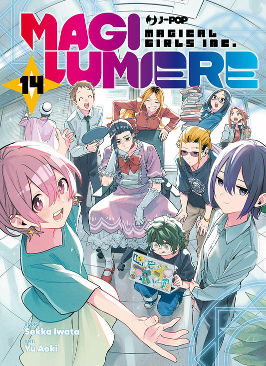 Copertina del manga Magilumiere 14. L'intero allegro e variegato team dell'azienda Magilumiere, tra abiti da ufficio, completi magici e abbigliamento casual, sorride felice in un ambiente lavorativo luminoso.