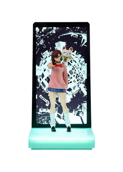 Figura espositiva di Momo Ayase da Dandadan per la linea Neon di Tsume Art. La statua ritrae Momo in divisa scolastica con maglione rosa e gonna blu con la mano tesa in avanti e Nonna Turbo in forma di gatto sulla spalla, inserita in un box espositivo con base illuminata da LED verde acqua e sfondo bianco e nero con palazzi urbani distorti.