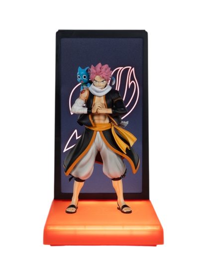 Figura espositiva di Natsu Dragneel da Fairy Tail con il gatto Happy sulla spalla per la linea Neon di Tsume Art. La statua ritrae Natsu con capelli rosa, pugni serrati e abiti tradizionali neri e arancioni, inserita in un box espositivo con base illuminata da LED arancioni e sfondo scuro recante il simbolo luminoso di Fairy Tail.
