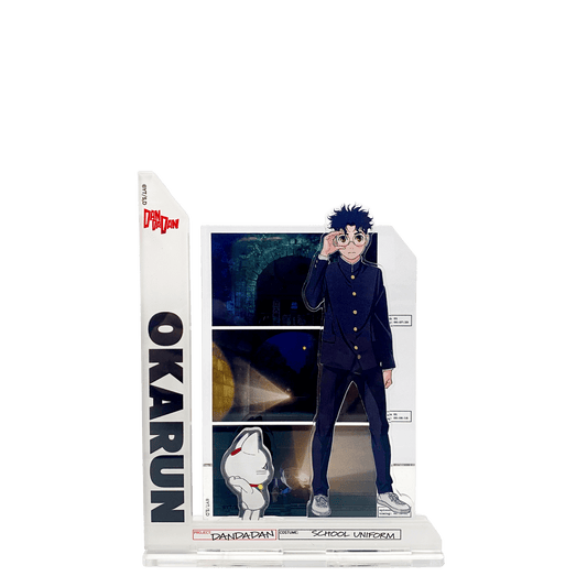 Acrylic standee composto da più parti assemblate: al centro il personaggio Okarun in divisa scolastica nera che si tocca gli occhiali; a sinistra una barra verticale con la scritta "OKARUN"; in basso una piccola figura della Turbo Granny in forma di gatto bianco; sullo sfondo un pannello rettangolare con scene scure tratte dall'anime/manga.