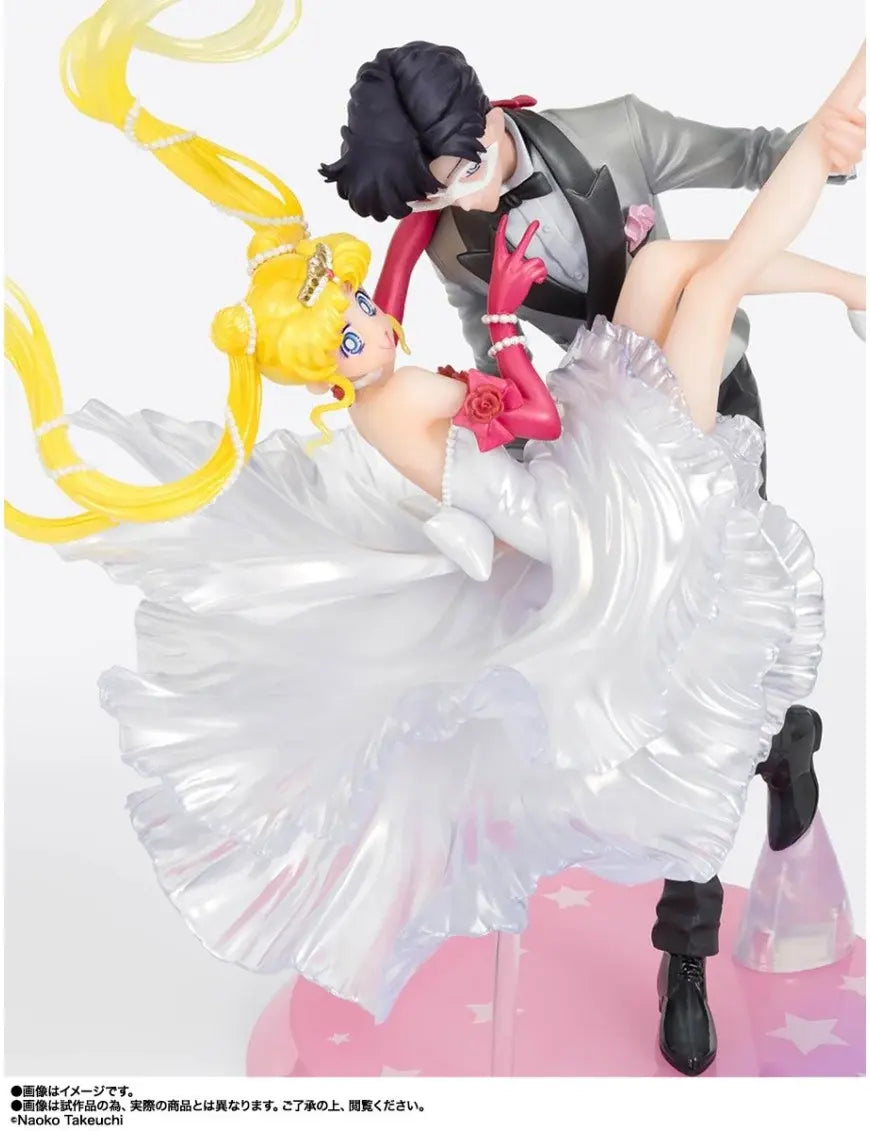 Figura da collezione di Sailor Moon e Tuxedo Mask della linea Figuarts Zero, visibile nel file vera.jpg. I due personaggi sono ritratti in un romantico passo di danza, con Tuxedo Mask in smoking grigio che solleva Sailor Moon, la quale indossa un sontuoso abito bianco fluttuante dalla finitura perlata.