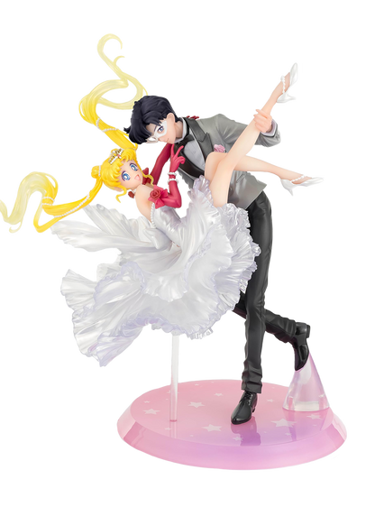 Figura da collezione di Sailor Moon e Tuxedo Mask della linea Figuarts Zero, visibile nel file vera.jpg. I due personaggi sono ritratti in un romantico passo di danza, con Tuxedo Mask in smoking grigio che solleva Sailor Moon, la quale indossa un sontuoso abito bianco fluttuante dalla finitura perlata.