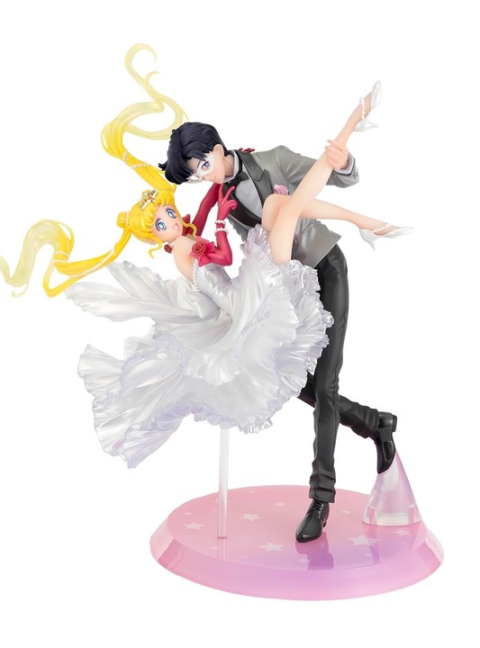 Figura da collezione di Sailor Moon e Tuxedo Mask della linea Figuarts Zero, visibile nel file vera.jpg. I due personaggi sono ritratti in un romantico passo di danza, con Tuxedo Mask in smoking grigio che solleva Sailor Moon, la quale indossa un sontuoso abito bianco fluttuante dalla finitura perlata.