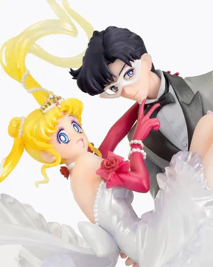 Figura da collezione di Sailor Moon e Tuxedo Mask della linea Figuarts Zero, visibile nel file vera.jpg. I due personaggi sono ritratti in un romantico passo di danza, con Tuxedo Mask in smoking grigio che solleva Sailor Moon, la quale indossa un sontuoso abito bianco fluttuante dalla finitura perlata.