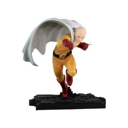 Immagine promozionale della statua in PVC di Saitama tratta dall'anime One Punch Man, prodotta da ABYstyle Studio, isolata su un profondo sfondo nero. Il personaggio, caratterizzato dalla testa calva e un'espressione concentrata, è ritratto in una posa d'azione dinamica, proteso in avanti in piena corsa con il braccio destro caricato all'indietro per sferrare un pugno. Indossa la sua divisa da eroe: una tuta gialla, guanti rossi, stivali rossi e un grande mantello bianco che si solleva ad arco dietro di lui