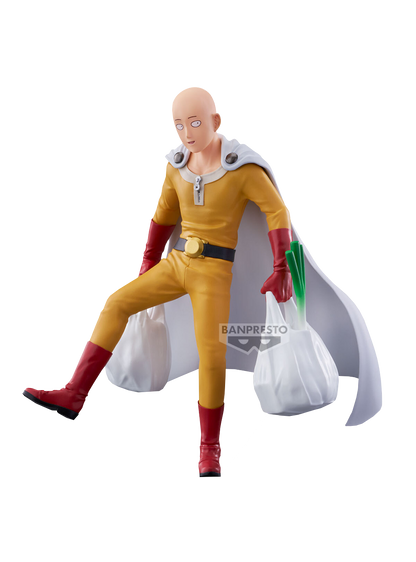 Figure in PVC di Saitama dalla serie One Punch Man, prodotta da Banpresto. Il personaggio, calvo e con un'espressione neutra, indossa il suo iconico costume da eroe composto da una tuta gialla, cintura nera con fibbia dorata, guanti e stivali rossi e un mantello bianco. È ritratto in una posa dinamica e comica mentre cammina sollevando una gamba e reggendo due sacchetti della spesa bianchi, da uno dei quali spunta un lungo porro verde.