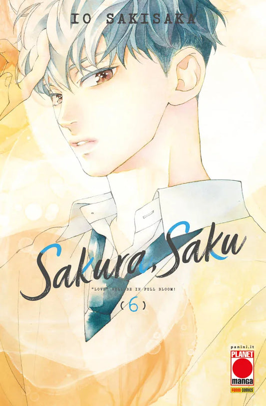 Copertina del sesto volume in italiano del manga shojo 'Sakura, Saku' di Io Sakisaka, edito da Panini Planet Manga. L'illustrazione artistica ad acquarello su fondo luminoso dai toni caldi ritrae in primo piano il coprotagonista Haruki Sakura con capelli corti sfumati dal grigio-azzurro al biondo, grandi occhi ambrati ed espressione assorta mentre indossa la divisa scolastica con camicia bianca e cravatta scura. Al centro spicca il titolo 'Sakura, Saku' in corsivo nero con dettagli azzurri, la frase '"LOVE"