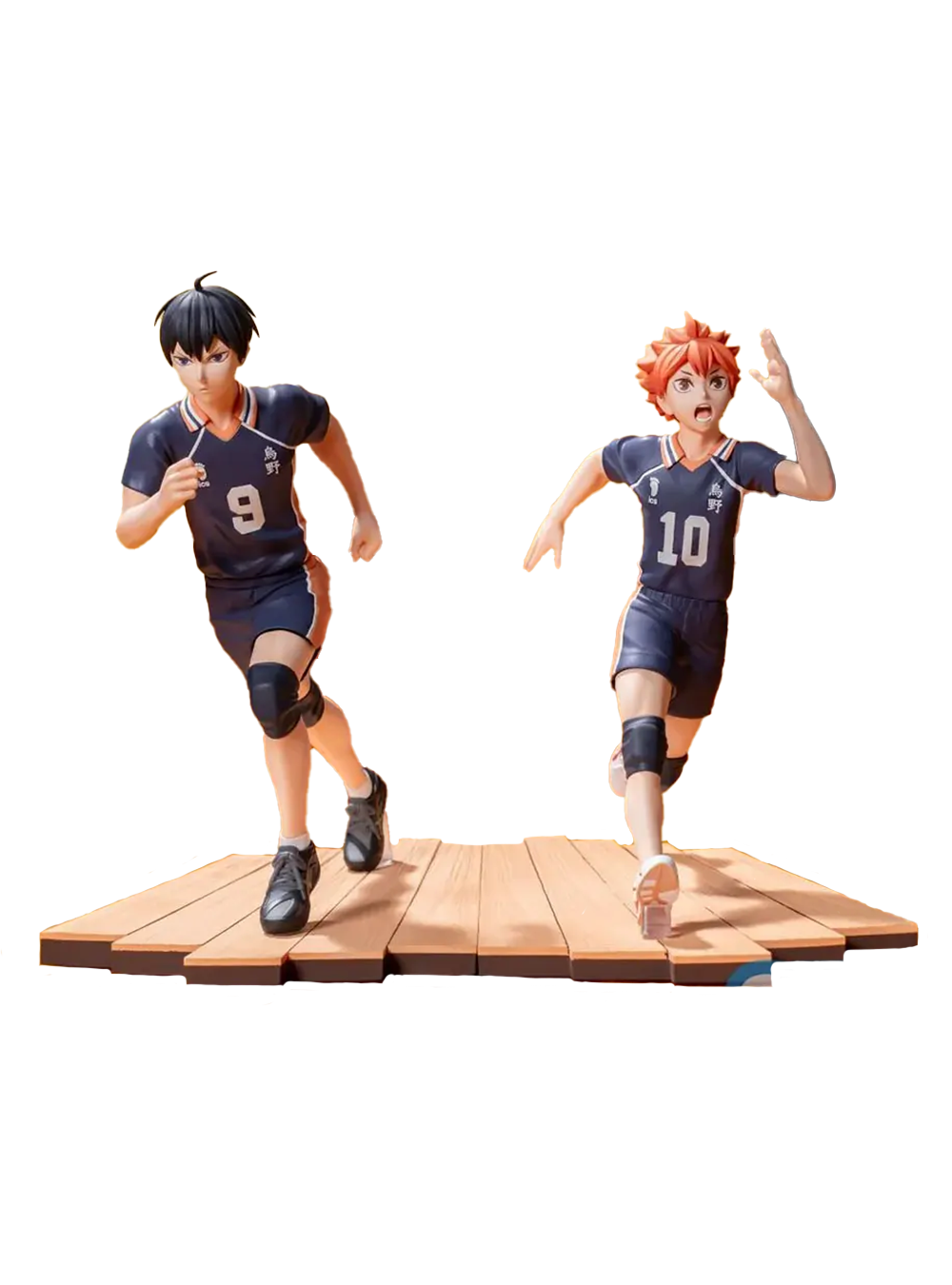Due figure da collezione dei personaggi Shoyo Hinata e Tobio Kageyama dall'anime Haikyu!!. I due ragazzi, uno con capelli arancioni e il numero 10 e l'altro con capelli neri e il numero 9, indossano divise da pallavolo scure e sono ritratti mentre corrono con espressioni decise su una base che riproduce il parquet di una palestra.