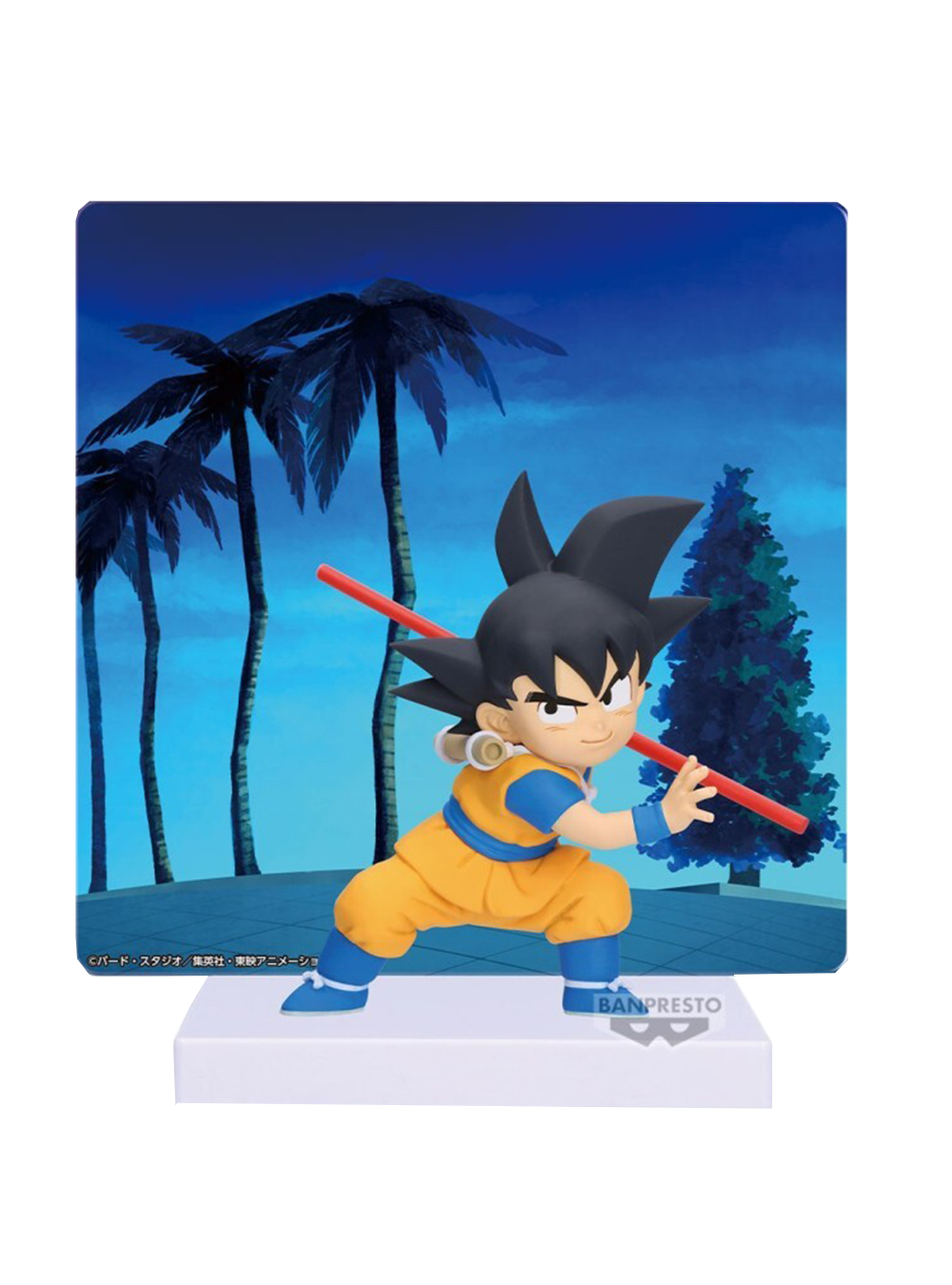 La figure di Son Goku (versione Mini da Dragon Ball Daima) in posa con il Bastone Nyoi rosso, posizionata davanti a un pannello illustrato con palme scure e un cielo blu notturno.