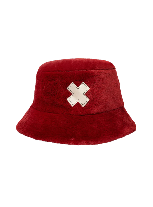 Bucket hat (cappello alla pescatora) realizzato in morbido tessuto effetto peluche di colore rosso. Sulla parte frontale è cucita in rilievo una grande croce bianca a forma di X con bordi impunturati, ispirata al personaggio di Tony Tony Chopper di One Piece.