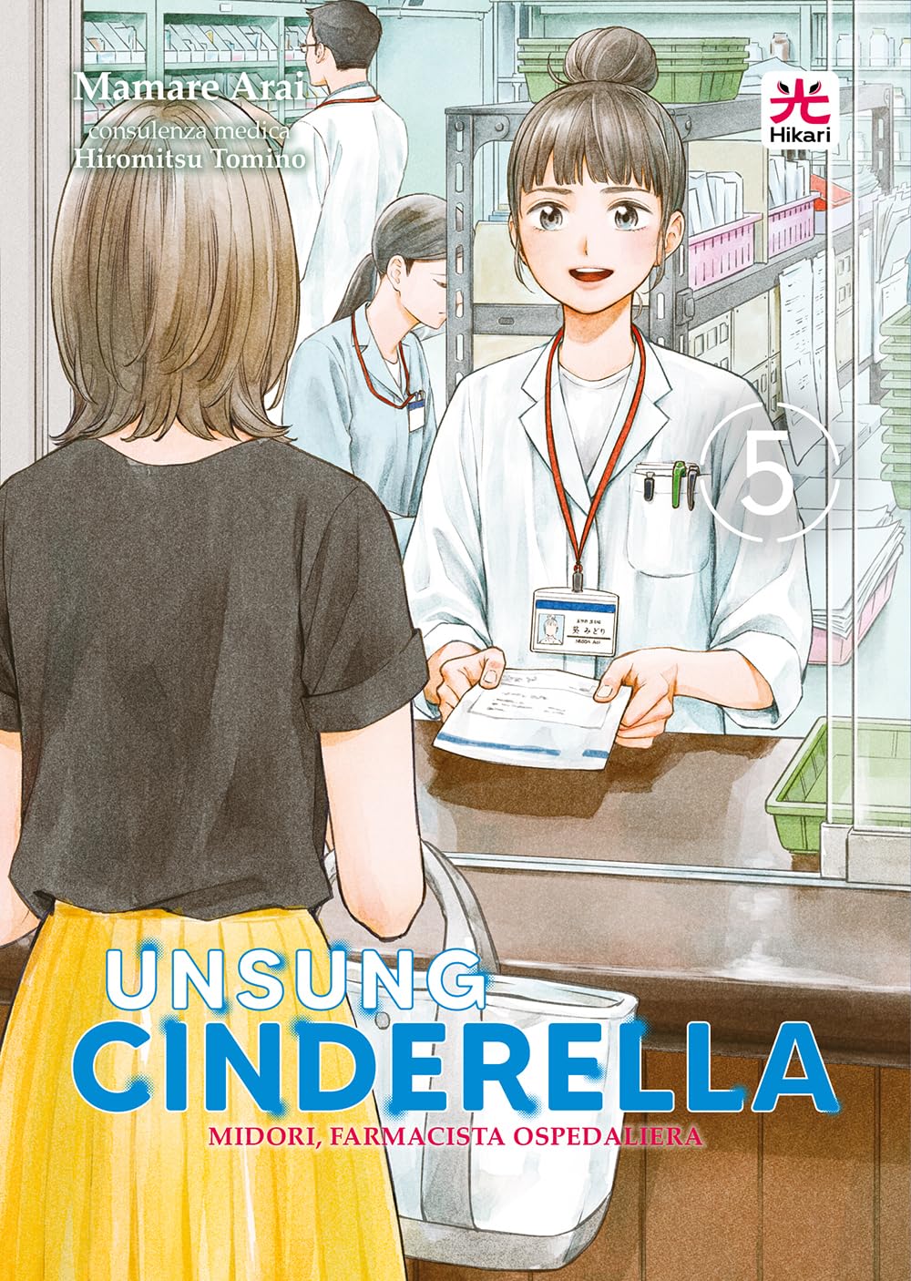 Copertina del quinto volume in italiano del manga medico 'Unsung Cinderella - Midori, farmacista ospedaliera' di Mamare Arai, edito da Hikari Edizioni. L'illustrazione ritrae la farmacista Midori Aoi con i capelli raccolti in uno chignon, camice bianco e tesserino di riconoscimento sorridente dietro il bancone della farmacia ospedaliera mentre consegna una busta medicinale a una paziente vista di spalle con maglia nera e gonna gialla, sormontata dal nome dell'autrice Mamare Arai in alto a sinistra, dal logo